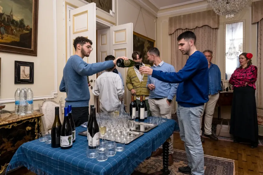Orateur en pleine présentation devant un public, dans un salon classique.
