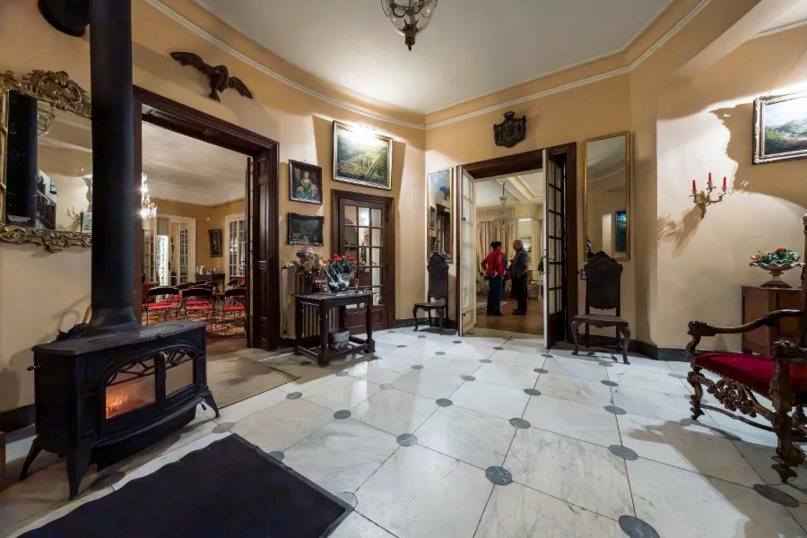 Hall d’un manoir préparé pour une réception, carrelage ancien et lumières chaudes.