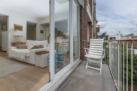 Chambre claire ouverte sur une terrasse en bois.