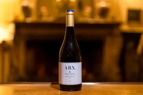 Bouteille de vin mise en scène près d’une cheminée, lumière chaude.