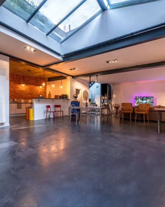 Loft lumineux sous verrière, sol en béton ciré et espace de travail ouvert.