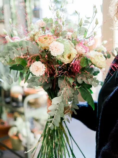 Grand bouquet champêtre de roses crème, pivoines et eucalyptus tenu par Sophie
