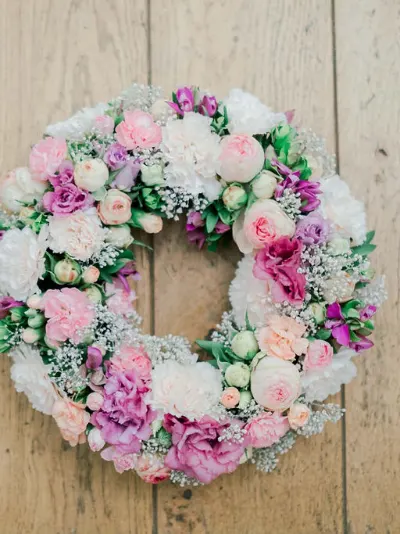 Couronne de roses, œillets et gypsophile dans des tons blancs, roses et mauves