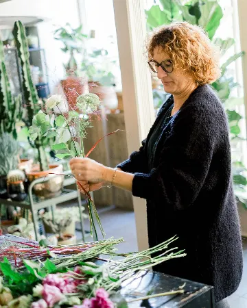 Sophie assemble un bouquet de fleurs blanches et roses sur l’établi