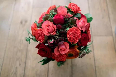 Bouquet rond de roses rouges, corail et renoncules vu de dessus