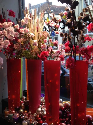 Vitrine de fêtes : grands vases rouges garnis de branches fleuries