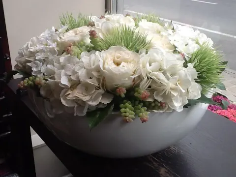 Composition d’hortensias et de roses blanches dans une large coupe blanche