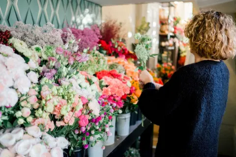 Sophie choisit des fleurs parmi les seaux colorés de la boutique