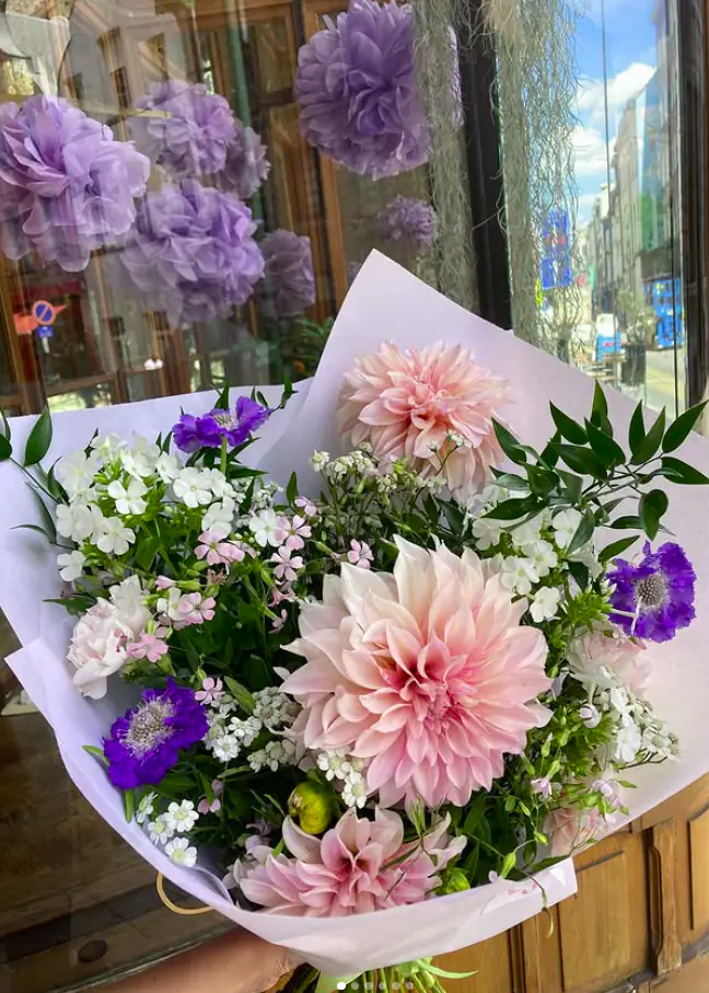 Boeket met roze dahlia’s, paarse scabiosa en witte bloemen voor de etalage van Versus in de Hoogstraat in Brussel
